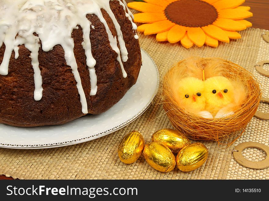 Easter decoration of table - traditional cake with icing, chocolate eggs and chicks. Easter decoration of table - traditional cake with icing, chocolate eggs and chicks