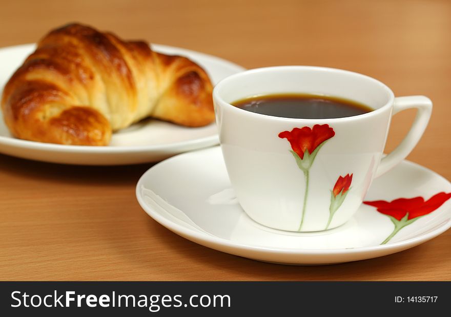Colorful cup with black coffee and croissant