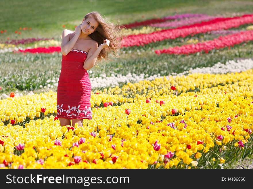 Beautiful girl in yellow and red tulips
