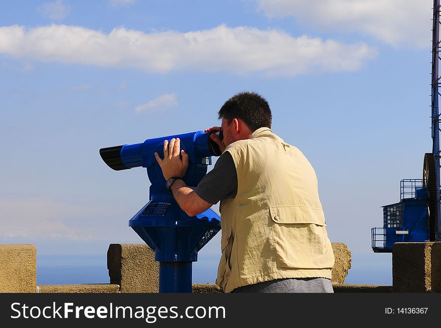 Man looking at the city of Barcelona from Tibidabo, using a coin operated pair of binoculars. Man looking at the city of Barcelona from Tibidabo, using a coin operated pair of binoculars.