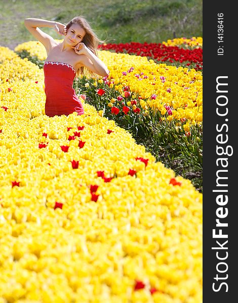 Young beautiful girl in yellow and red tulips