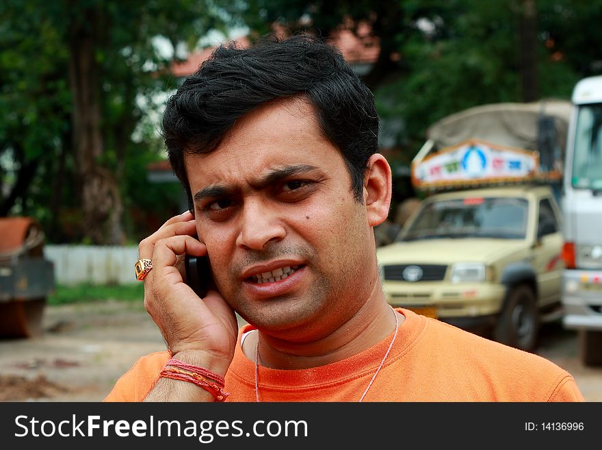 A young man showing expressions of extreme disturbance and stress while taking a phone call. A young man showing expressions of extreme disturbance and stress while taking a phone call.