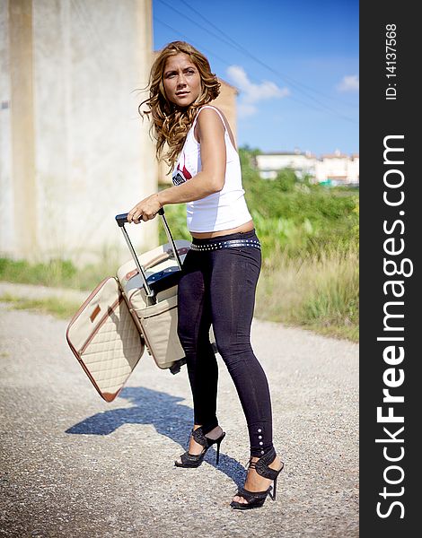 Beautiful fashion female model with blond and curly hair holding a travelling bag. Beautiful fashion female model with blond and curly hair holding a travelling bag