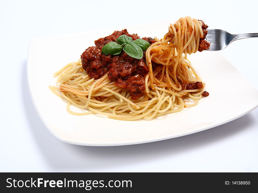 Spaghetti bolognese on a plate and some on a fork on white