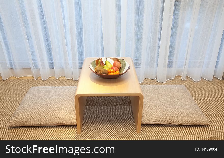 Cushion and tea table near the window.