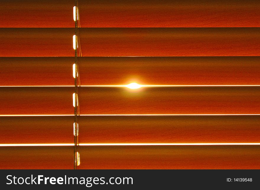 Close-up of orange jalousie in office lit by setting sun