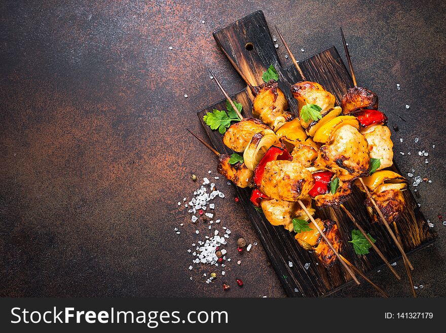 Chicken kebab or shashlik with vegetables on black stone table. Barbeque meat dish. Top view copy space. Chicken kebab or shashlik with vegetables on black stone table. Barbeque meat dish. Top view copy space.