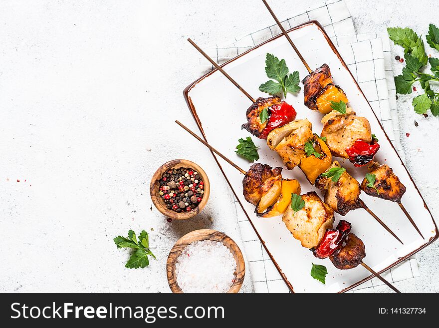 Chicken kebab or shashlik with vegetables on white stone table. Barbeque dish. Top view with copy space. Chicken kebab or shashlik with vegetables on white stone table. Barbeque dish. Top view with copy space.