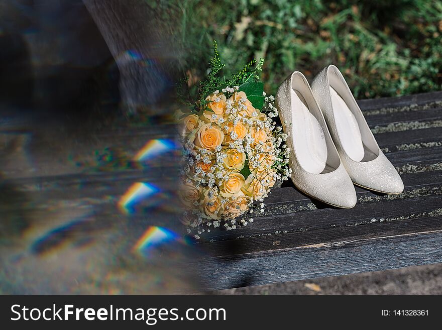 Wedding bouquet rings and shoes of the bride in the sun.