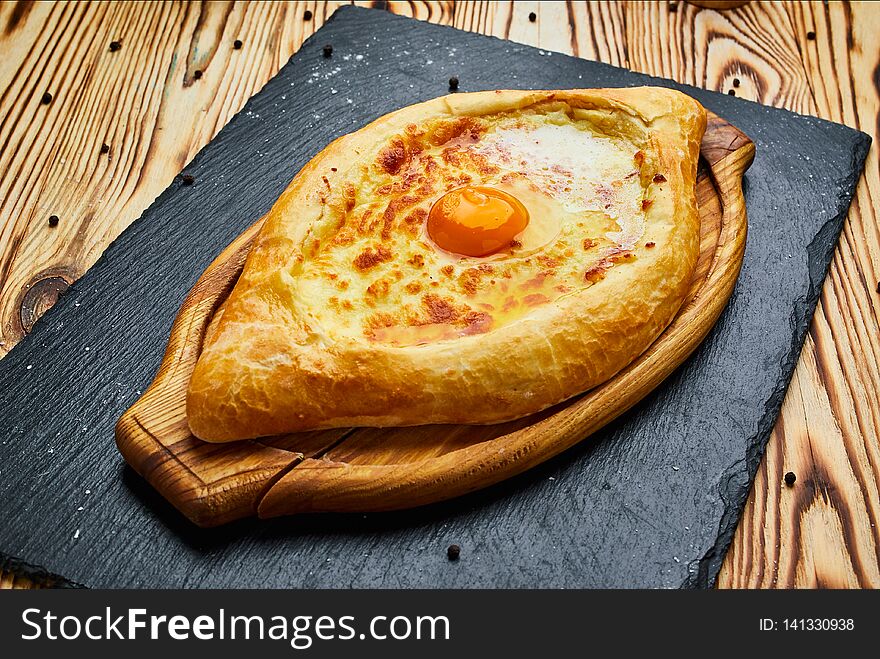 Ajarian Khachapuri traditional Georgian cheese pastry with eggs on cutting board . Homemade baking. Open pie with mozzarella