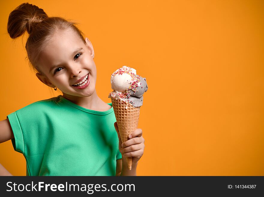 Little baby girl kid eating vanilla ice cream in waffles cone on yellow background. Banner