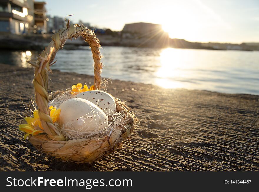 Small basket with two easter eggs on the sea doc on golden hour easter concept