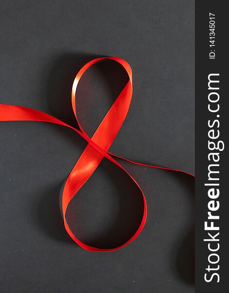 8 March Women`s day background. Red ribbon eight on a black board