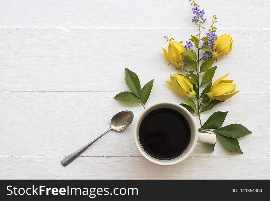 Hot coffee espresso with flower ylang ylang decoration flat lay style on table white