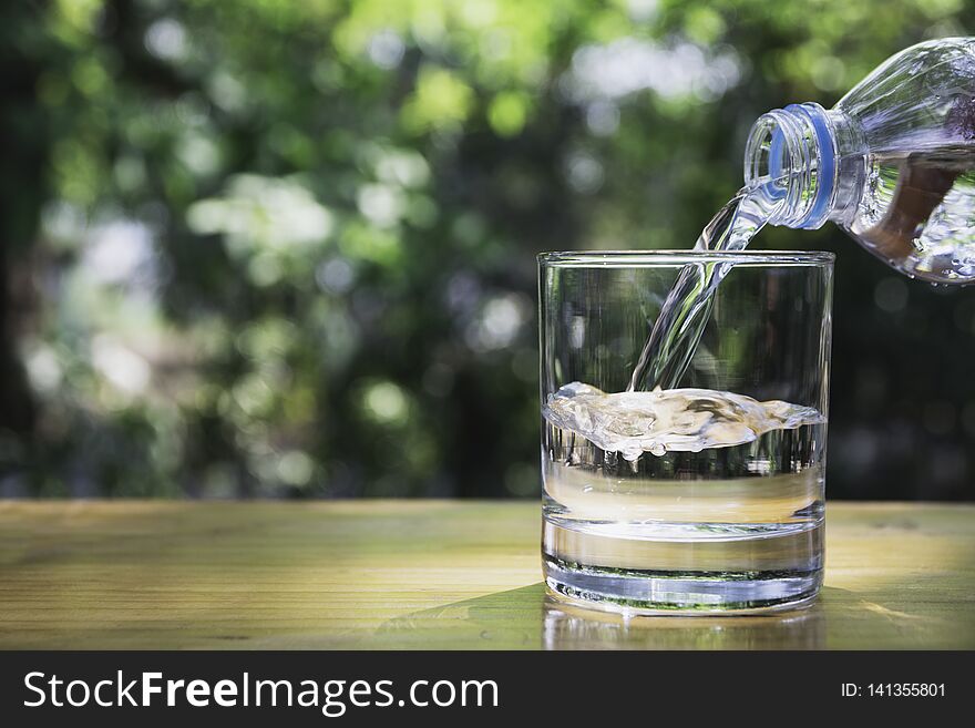 Hand holding water bottle on wooden in nature background