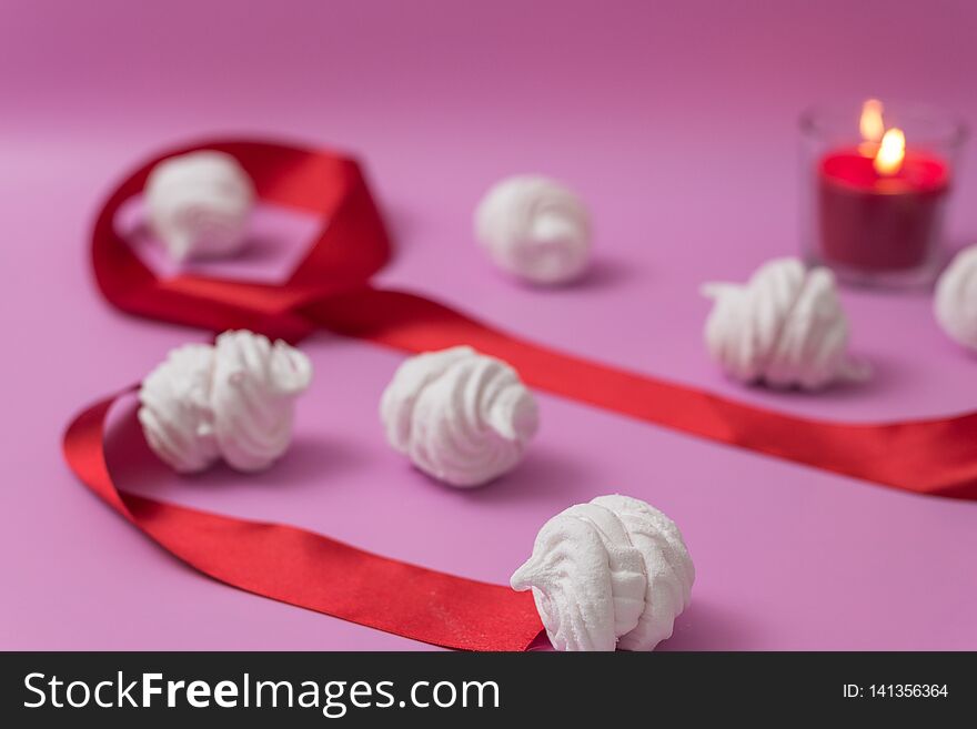 White homemade zefir or marshmallow on pink background with red candle