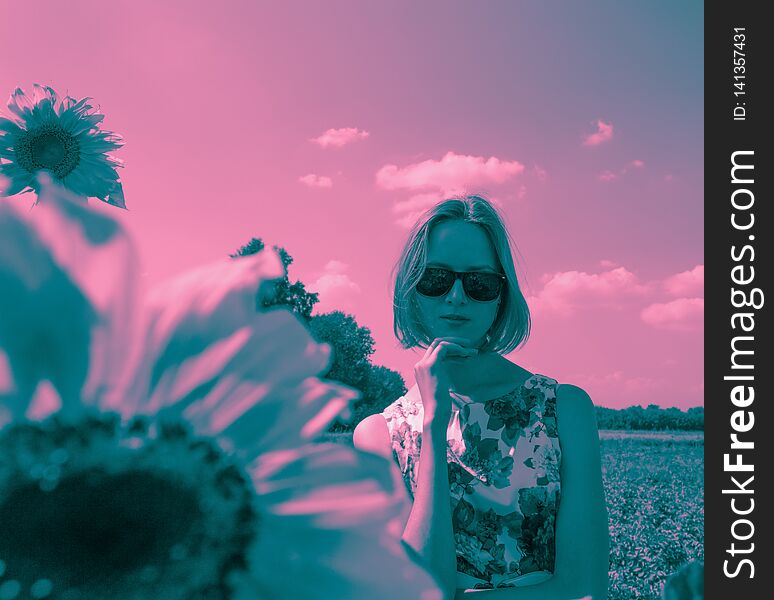 Duotone portrait of young woman in sunglasses and floral dress staing in the field