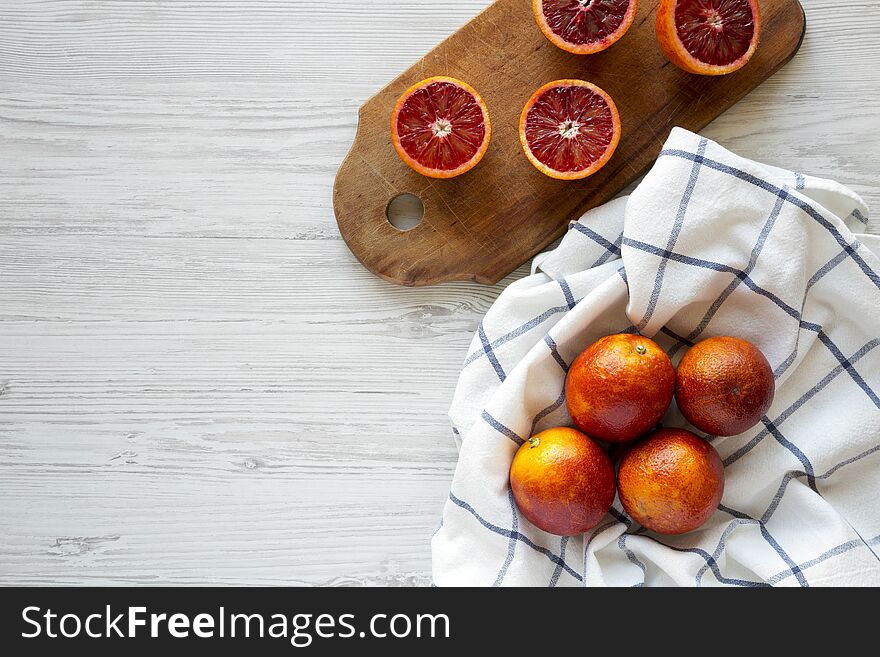 Whole and halved blood oranges on a white wooden background, top view. Flat lay, overhead, from above. Copy space