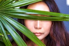 A Beautiful Woman Is Hiding Behind Palm Leaves. Eastern Beauty And Skin Care. Stock Images