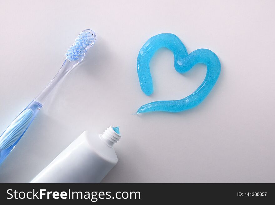 Dental health concept with toothbrush tube and toothpaste heart on white table detail. Horizontal composition. Top view. Dental health concept with toothbrush tube and toothpaste heart on white table detail. Horizontal composition. Top view