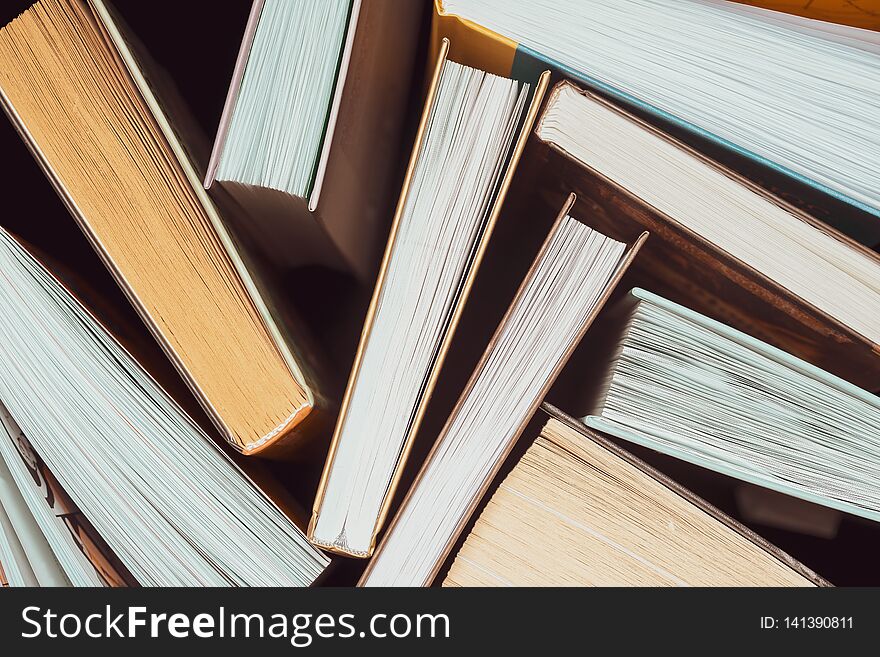 A stack of thick open books stand on a dark background. Back to school. Education background. A stack of thick open books stand on a dark background. Back to school. Education background