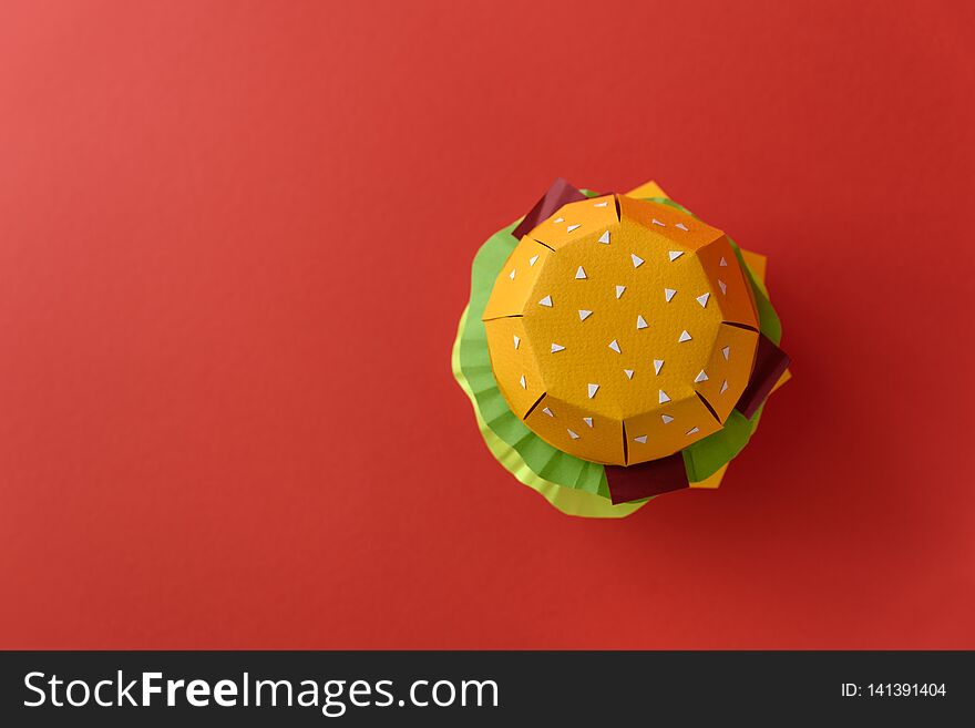 Paper cheeseburger with beef, cheese, tomato, lettuce, onion, bacon and sauce on red background. Copy space. Creative or art food