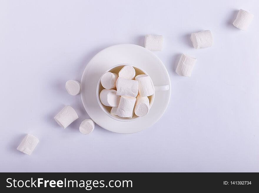 Empty ceramic cup with marshmallows on a saucer, on a white background. Hard shadow from the sun, the concept of morning