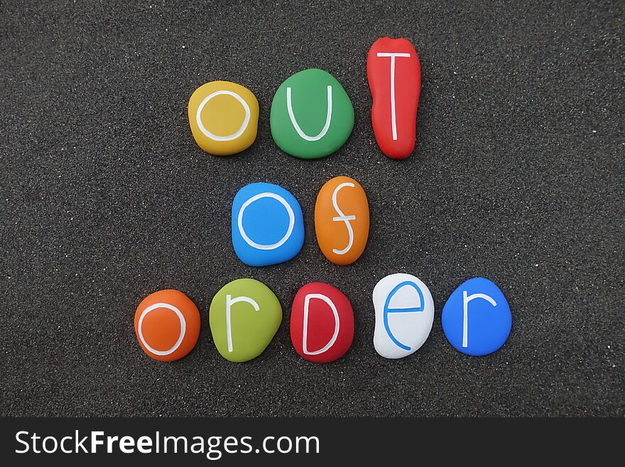 Out Of Order Message With A Composition Of Multi Colored Sea Stones Over Black Volcanic Sand