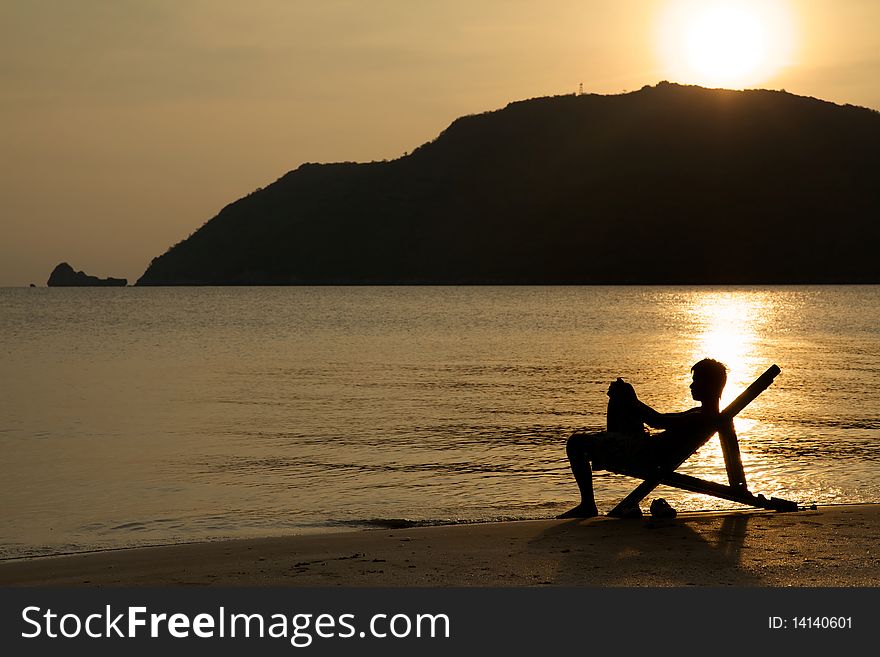 A silhouette of an anonymous young man relaxing on the beach. A silhouette of an anonymous young man relaxing on the beach.