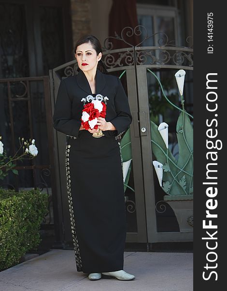 Latino Woman in trational dress standing in front of gate