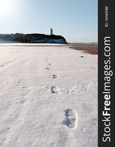 Footprints on an empty beach with castle in background on a cold winters day. Footprints on an empty beach with castle in background on a cold winters day