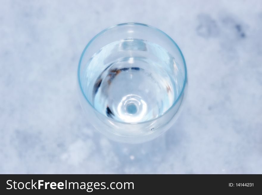 Glass of cool water in icy crisp snow