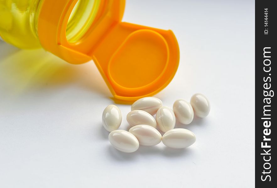 Close up of yellow bottle and white capsules