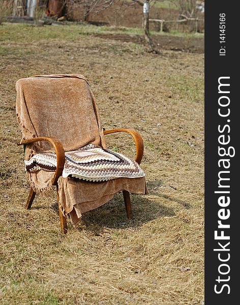 Old-fashioned brown garden chair with a textile cover and a wool knitted pillow. Old-fashioned brown garden chair with a textile cover and a wool knitted pillow