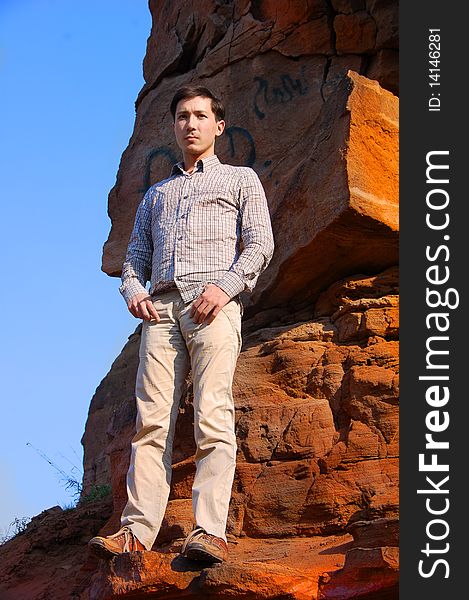 Young man on the rocks against the blue sky. Young man on the rocks against the blue sky