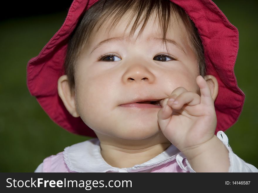 Cute little girl sucking finger in garden