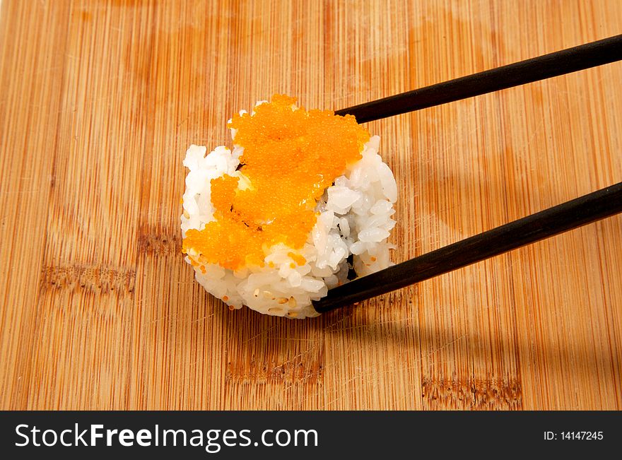 Piece of chopped scallop roll being picked up with a pair of chop sticks. Close up. Piece of chopped scallop roll being picked up with a pair of chop sticks. Close up