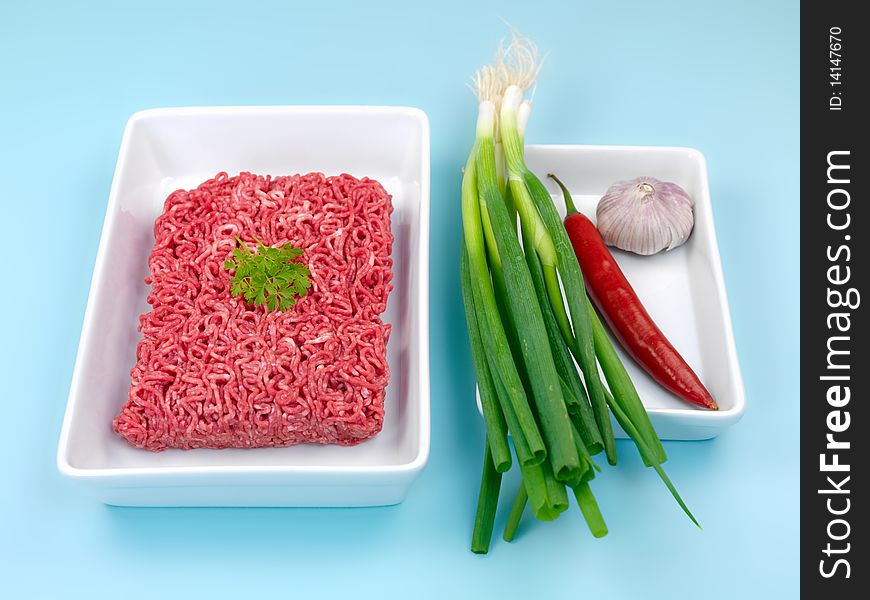 Fresh minced beef and vegetables isolated against a blue background. Fresh minced beef and vegetables isolated against a blue background