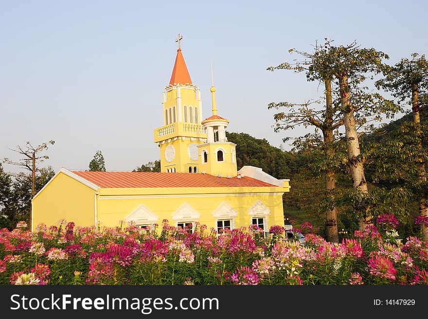 A yellow church.In the garden.Colorful.with tree and flower.