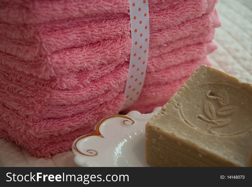 Rustic soap in a dish with a pile of washcloths nearby. Rustic soap in a dish with a pile of washcloths nearby.