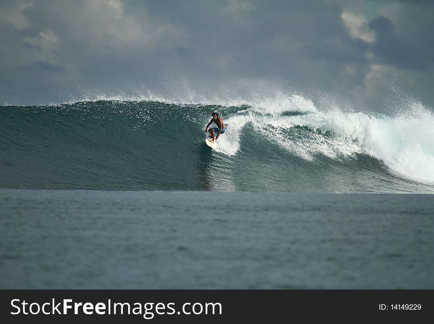 Surfer riding perfect blue wave, Indonesia. Surfer riding perfect blue wave, Indonesia