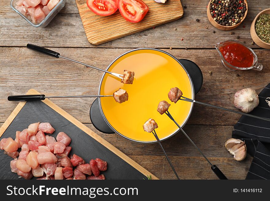 Flat lay composition with fondue pot and meat