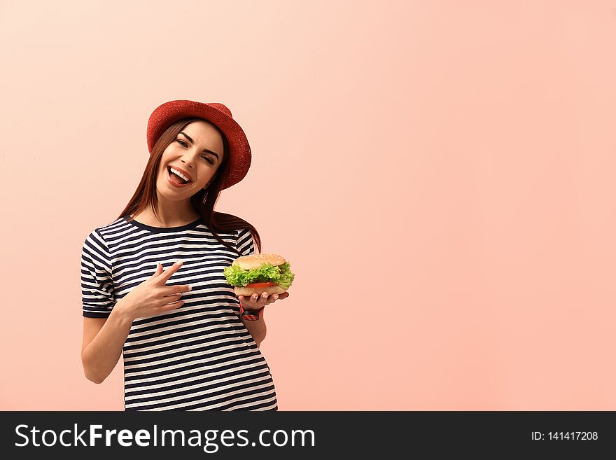 Young woman with tasty burger on color background.