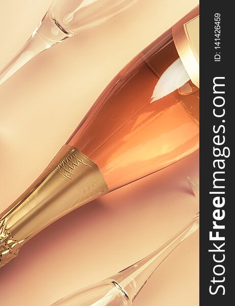Bottle with pink sparkling wine or rose champagne and two glasses, trendy pink background with place for text, holiday or date