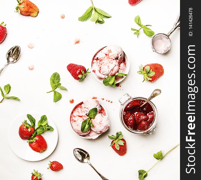 Strawberry ice cream with jam topping, decorated with green mint leaves, gray kitchen table background, top view. Strawberry ice cream with jam topping, decorated with green mint leaves, gray kitchen table background, top view