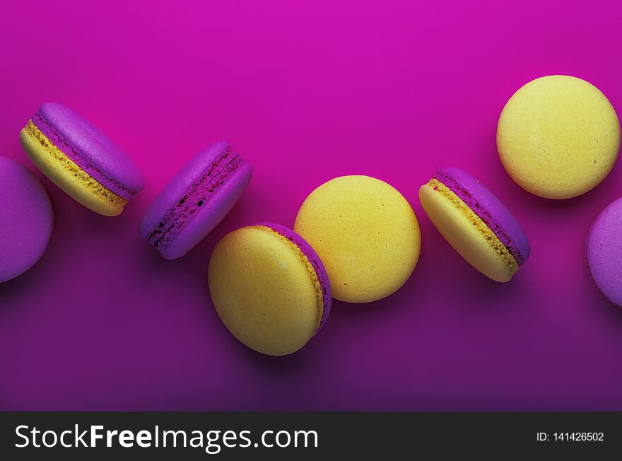 Pink yellow macaroons on soft pink background table, place for text, minimalism style, violet purple neon color, top view
