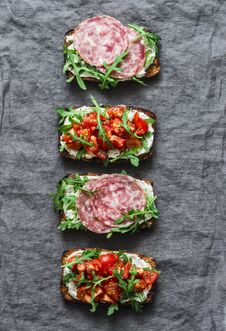 Tomatoes, Italian Sausage And Rocket Salad Whole Grain Bread Sandwiches On A Gray Background, Top View. Copy Space Royalty Free Stock Image