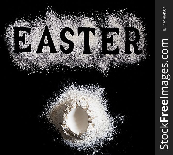 Letters EASTER made with sieved flour and Handrful of flour with with egg shape hole in the center on black background, Easter