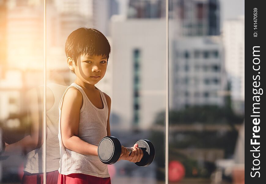 Boy is working out with dumbbell by the windows city