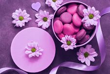 Purple And Pink Macaroons In A Gift Box On A Beautiful Purple Background Decorated With Flowers. Top View Stock Photos